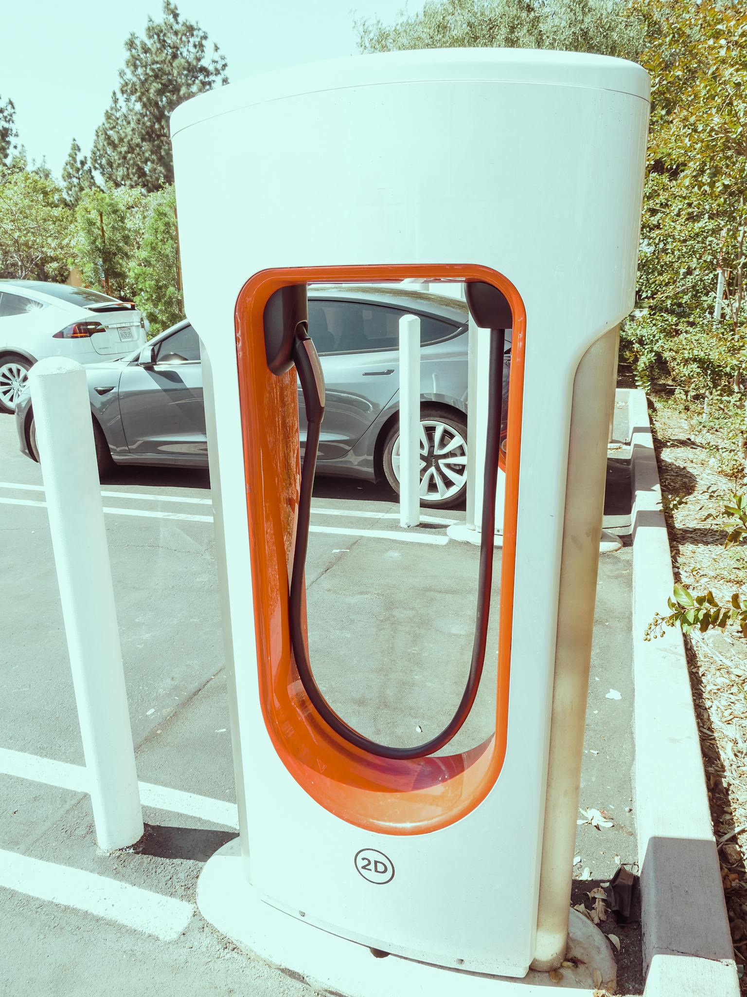 Close-up of a sleek electric car charging station in an outdoor parking lot.