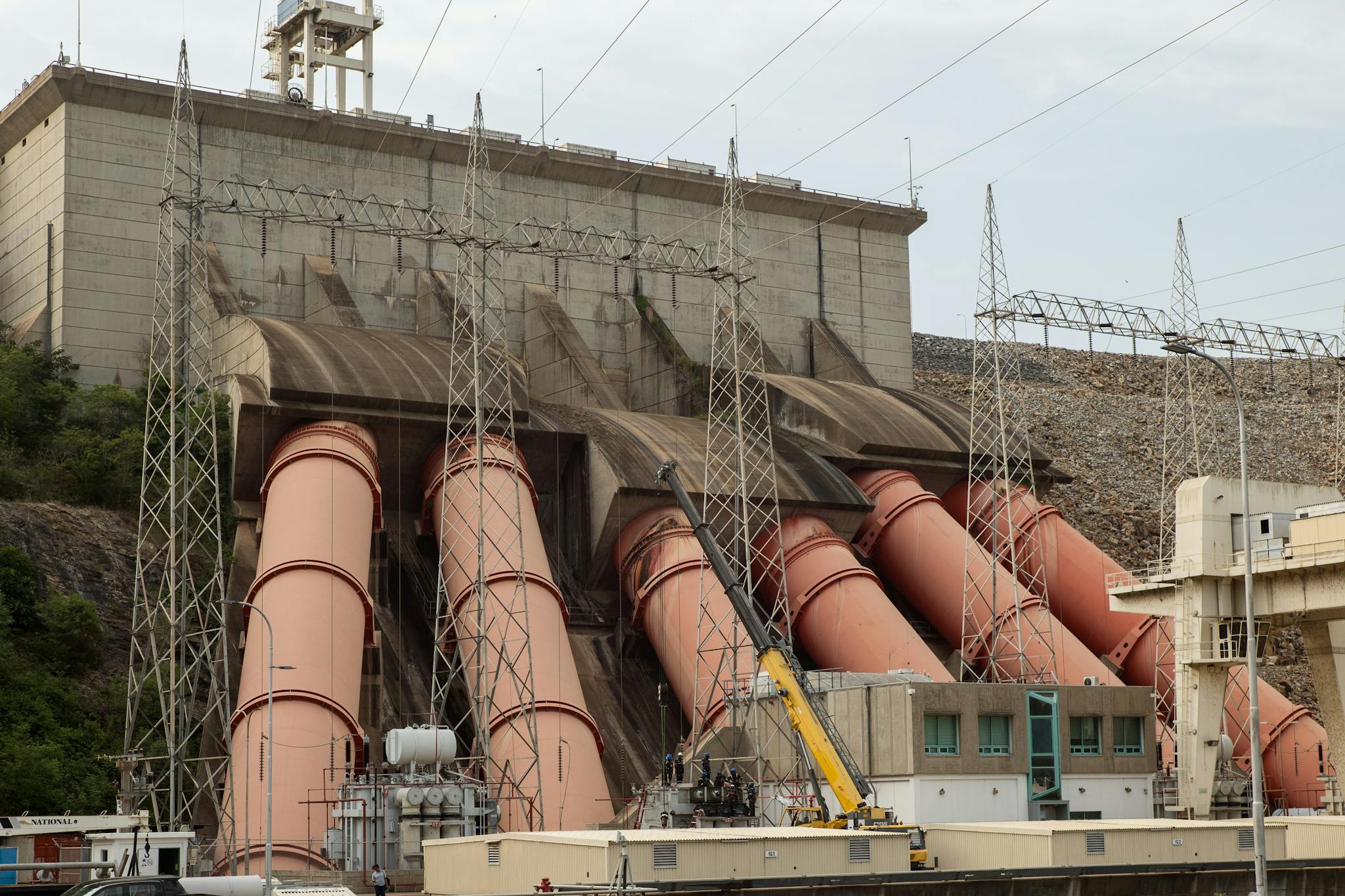 Industrial view of a massive hydroelectric dam with large pipes and power lines.